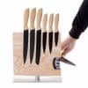 Magnetischer Messerblock aus Holz mit sechs Küchenmessern und integriertem Messerschärfer, Lifestyle-Abbildung mit Hand beim Schärfen.