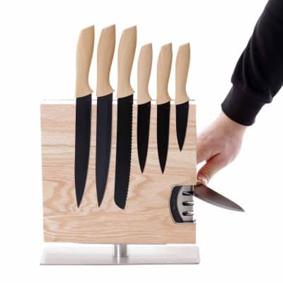 Magnetischer Messerblock aus Holz mit sechs Küchenmessern und integriertem Messerschärfer, Lifestyle-Abbildung mit Hand beim Schärfen.