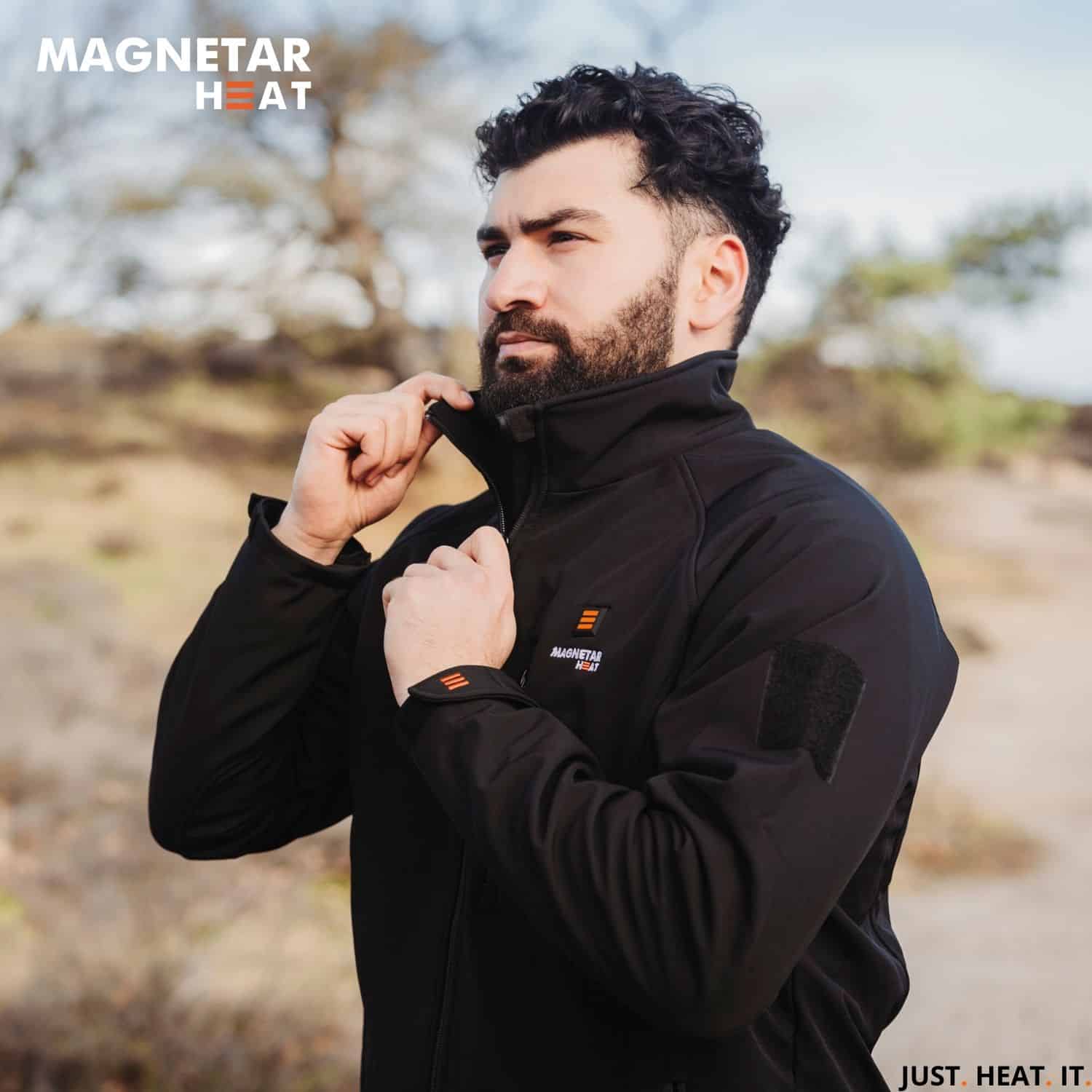 Outdooraufnahme eines Mannes in schwarzer beheizbarer Magnetar Heat Softshelljacke mit hohem Kragen, ideal für kalte Tage.