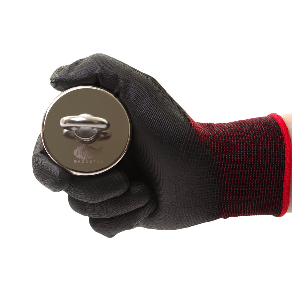 Detailaufnahme eines runden Magnetar Neodym-Bergemagneten mit Öse, gehalten in schwarzem Schutzhandschuh – kompakt und stark fürs Magnetfischen.