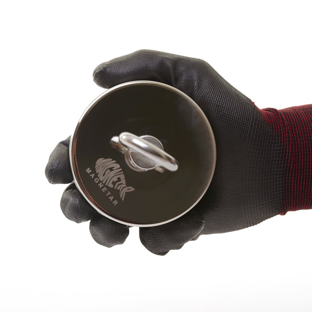 Detailaufnahme eines runden Magnetar Neodym-Bergemagneten mit Öse, gehalten in schwarzem Schutzhandschuh – kompakt und stark fürs Magnetfischen.