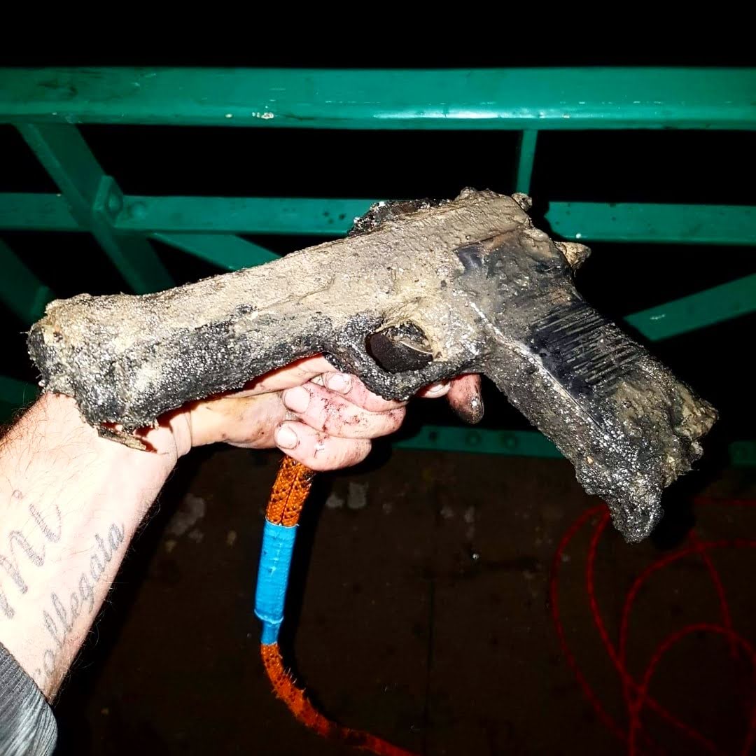 Fundfoto beim Magnetfischen: stark verschlammte, rostige Pistole, mit Seil aus dem Wasser geborgen – zeigt die Kraft des Bergemagnets.