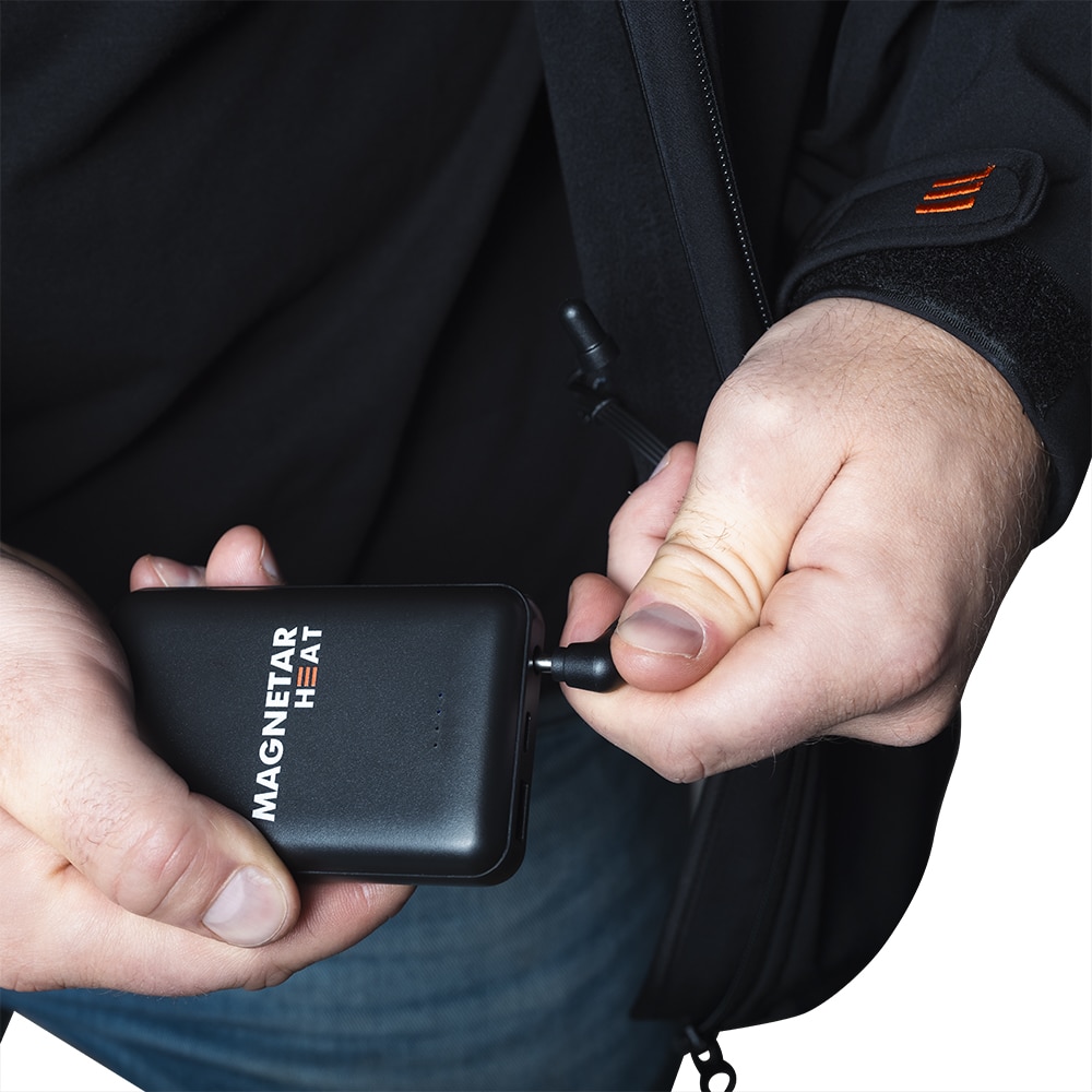Detailfoto einer beheizbaren Jacke mit angeschlossener Powerbank – einfache Energieversorgung für langanhaltende Wärme im Outdoor-Einsatz.