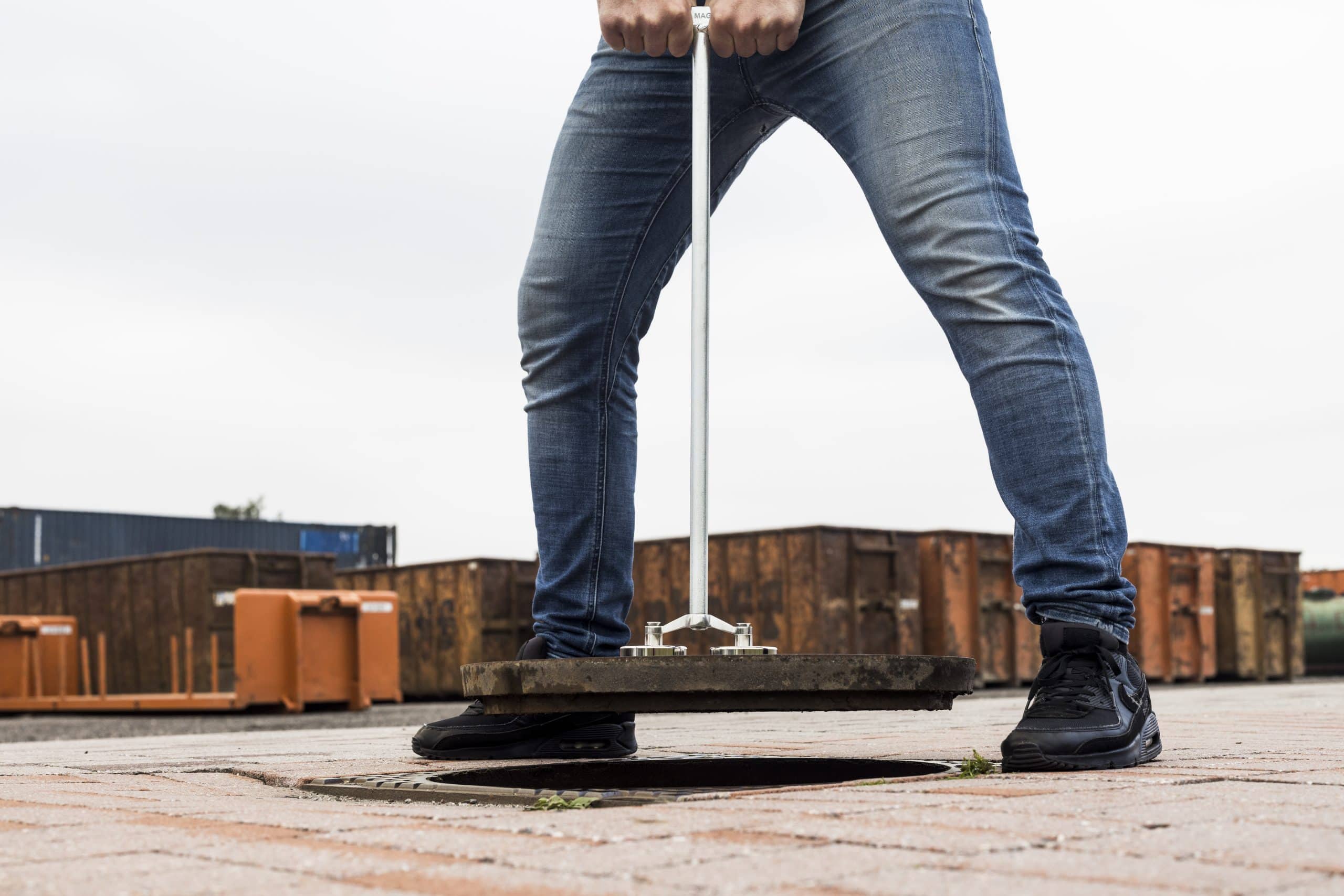 Lifestylefoto Kanaldeckelheber mit Neodym-Magneten im Einsatz, erleichtert das Anheben schwerer Schachtabdeckungen bei Kommunalarbeiten.